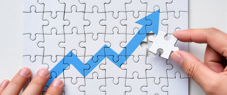 Close-up Of Human Hand Holding Jigsaw Puzzle Piece With Blue Arrowの素材