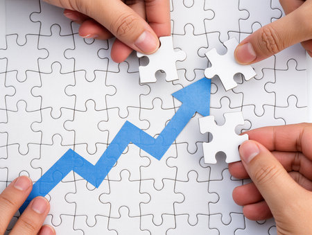 Close up of business people hands assembling jigsaw puzzle with rising arrowの素材