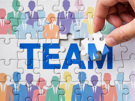 Hand put missing jigsaw puzzle piece with Team word, business conceptの素材