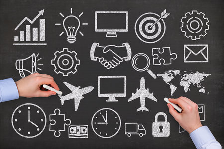 businessman drawing business strategy on blackboard with chalk and gear iconsの素材