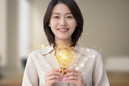 businesswoman holding a glowing light bulb in front of her, asianの素材