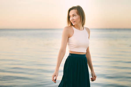 a woman in a the skirt and top is walking along the beachの写真素材