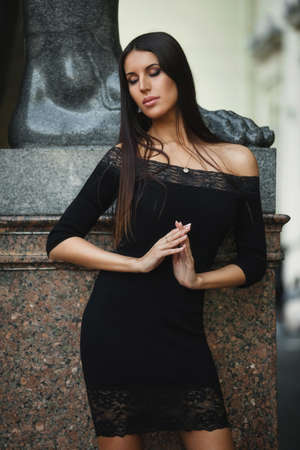 Attractive woman in stylish dress posing on city street with eyes closed.の写真素材