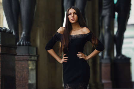 Attractive woman in stylish dress posing on city street looking at cameraの写真素材