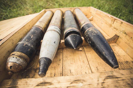 Ammunition in wooden box composed in row lying on green grass in field.の写真素材