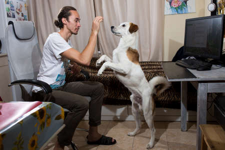 Young man is playing with his dog in living room