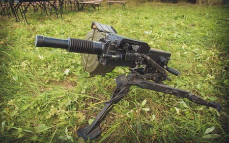 Front view at grenade launcher weapon against tanks lying on ground.