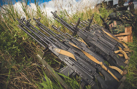 Front view of row of various weapon lying on ground.