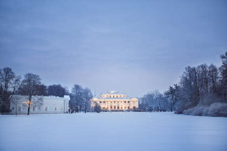 Winter park in the evening covered with snow with a palace backgroundの写真素材