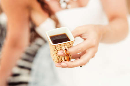 Close up view at a woman in white dress holding cup in african style with black coffeeの写真素材