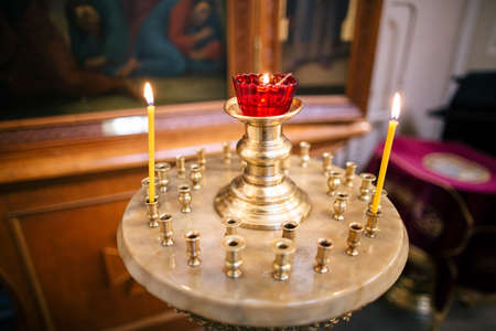 Golden chandelier with candles burning inside of church.