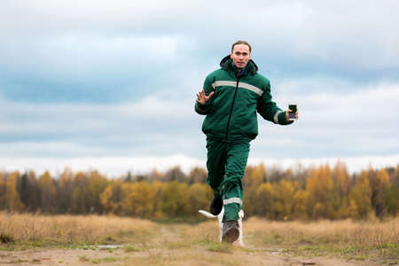 Man running with two dogs while training them on autumn lawn.