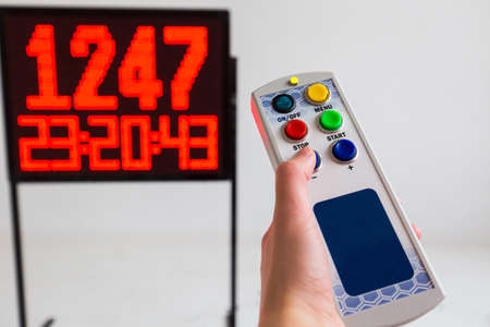 Crop view of somebody's hand pressing a button on a control panel. Red led light illumination numbers on black digital electric display isolated on white is background.の写真素材