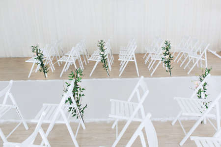 Indoor wedding ceremony with white wedding arch decorated with flowers and big white candles.の写真素材