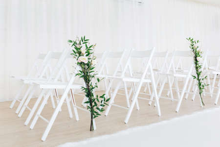 Indoor wedding ceremony with white wedding arch decorated with flowers and big white candles.の写真素材