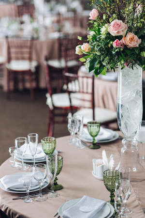 Beautiful composition with flowers on the tables and candles for guests at a wedding or a birthday...