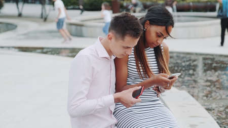 Black girlfriend with boyfriend on date not talking, but chatting with somebody by smartphones. They probably have problem with communication.の写真素材