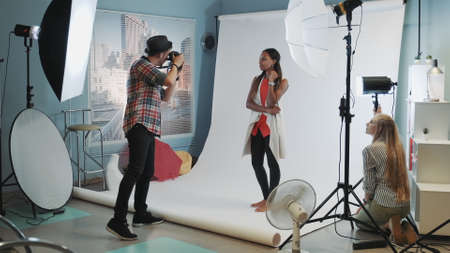Photo session in modern studio: photographer taking photos of the black model an