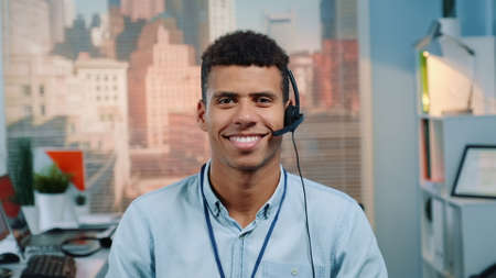 Portrait of mixed-race customer service operator in a headset smiling to the camera. There are skyscrapers in the background.の写真素材