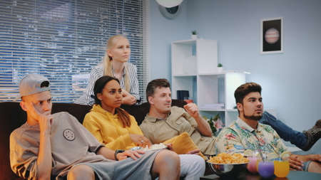 Sport fans watching TV together and feeling sad and stressed of match fail. There are skyscrapers in the background.の写真素材