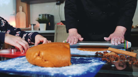 Mother and daughter making gingerbread cookies in the kitchen at home. Family culinary and traditions concept.の写真素材