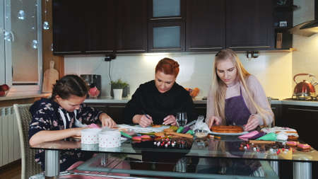 Mothers home business: making gingerbread cookies for the client. Two women and a girl trying to make the order perfectly.の写真素材