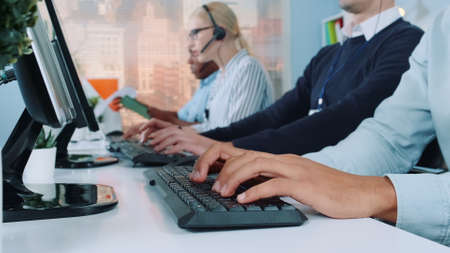 Medium shot of operators hands typing on keyboard in modern office. People are busy working on the computer.の写真素材