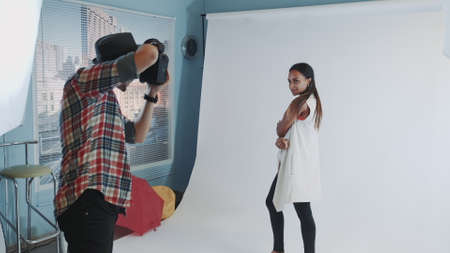 Behind the scenes on photo shoot: professional photographer working in studio by taking photos of black model. Photo shoot for stylish fashion magazine.の写真素材