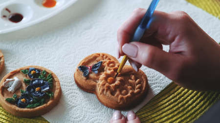 Decorating gingerbread cookie of original shape with brush and food colors. Sweet cookies with ornaments.の写真素材