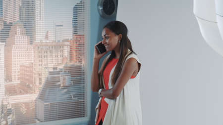 Attractive african model speaking with somebody on smartphone during photo shoot break in studio. Fashion magazine photoshootの写真素材