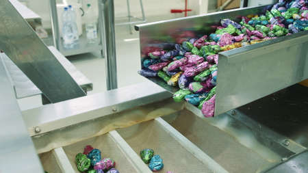 Candy factory. Sweets spilling from conveyor. Bunch of wrapped candies falling from conveyor on...