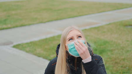 Close-up shot of young female looking into the sky and putting on medical mask. Virus outbreak...