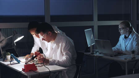 Multiracial man and woman checking motherboard with multimeter tester in electronics laboratory. They discussing and explaining different thingsの写真素材