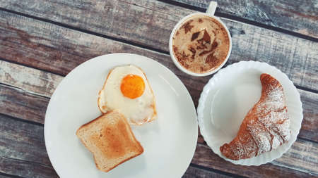 Close-up of light lunch dish with fried egg, toast and croissantの写真素材
