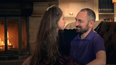 Daughters time with father: smiling, embracing and having fun near fireplace at home. Family happiness conceptの写真素材