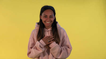 Multiracial girl laughing at somebody. There is yellow background.の写真素材