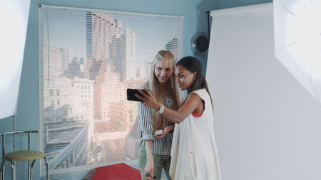 Backstage of the photo shoot: attractive black model making selfie with pretty make-up artist. They smiling and having fun.の写真素材