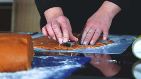 Close-up shot of making gingerbread cookies with cookie cutter. Woman making cookies on black table in the kitchen.の写真素材