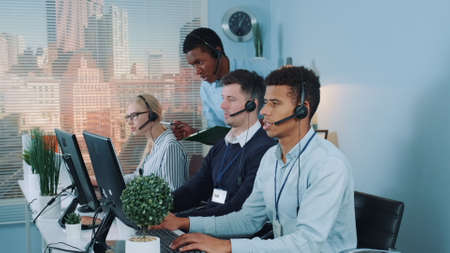 Chief black manager of the call center giving recommendations to customer service representative, which making international call to the client.の写真素材