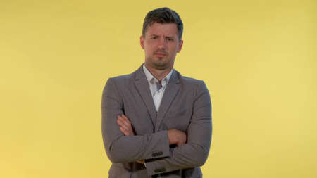 Handsome young businessman putting his hand out and saying what . He has suit on. Yellow background.の写真素材
