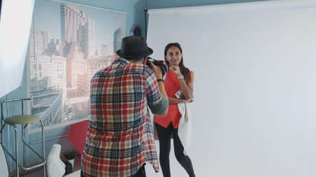 Behind the scenes on photo shoot: professional photographer working in studio by taking photos of black model. Photo shoot for stylish fashion magazine.の写真素材