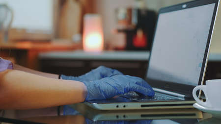 Close-up shot of womans hands in medical gloves typing on keyboard. In the background warm lights.の写真素材