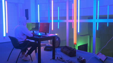 Hacker working place: hacker working in a room with colored neon lights. He writing hacker program.