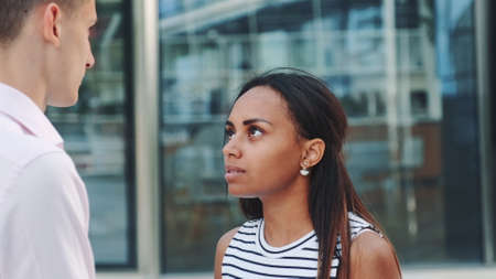 Close-up of young black lady quarreling with her boyfriend in the street and going away. There is a big office building in the background.の写真素材