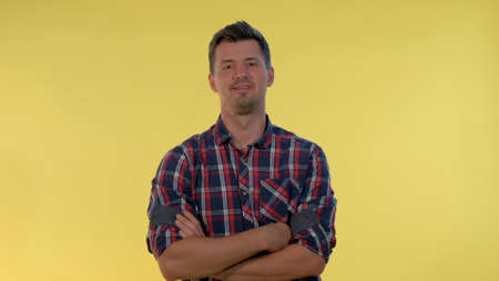 Tall young man deriding somebody, making fun of someone on yellow background. He is in checkered shirt.の写真素材