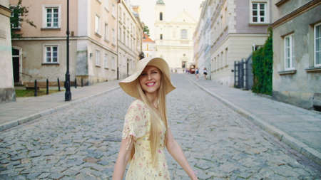 Smiling woman walking on town street. Smiling woman looking back at camera while walking on street of old town.の写真素材