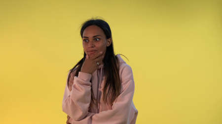 African young woman widely opening her mouth in astonishment on yellow background. She has heard some excellent news.の写真素材