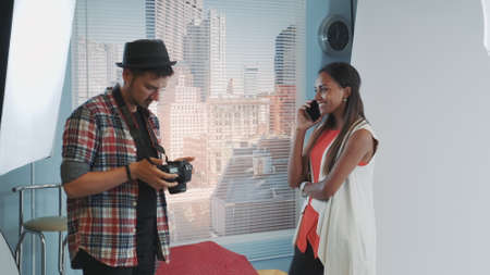 Professional photographer asking model to stop talking on smartphone and continue working. Black woman doesnt take care, she keeps talking.の写真素材