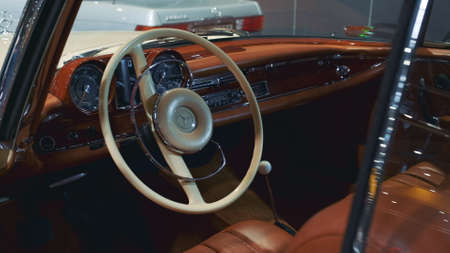 Vintage car interior: shiny brown dashboard, leather sits and milk steering wheel. Close-up shot....