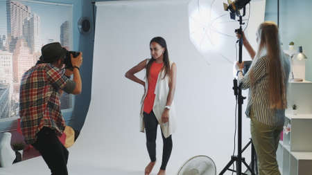 Behind the scenes on photo shoot: photographer asking assistant to direct the lighting to the model. They working in professional studio photo shoot.の写真素材